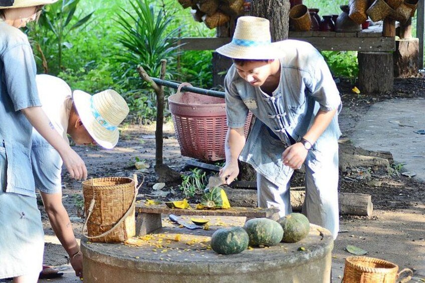 People working with baskets and a large container, possibly in a rural setting. 1
