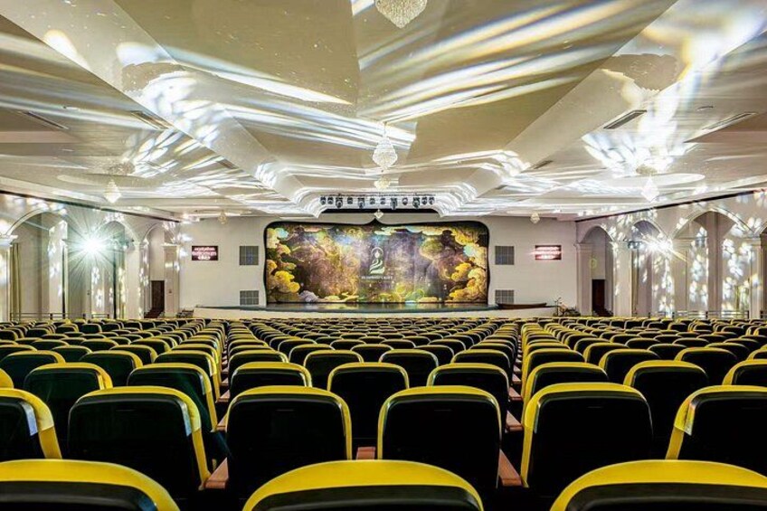 Ein Theater mit gelb-schwarz gestreiften Sitzreihen, einer großen Leinwand im Vordergrund und einer verzierten Decke. 5