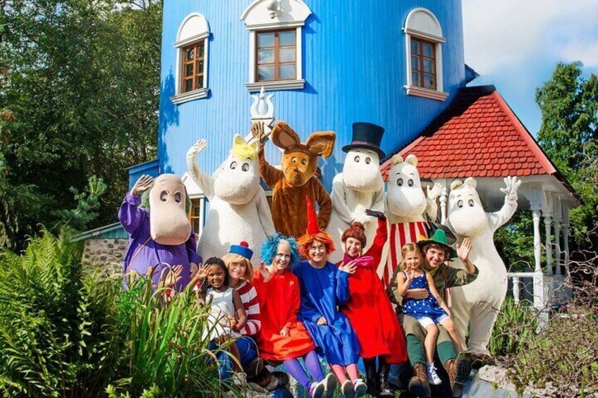 A group of people in costumes in front of a blue house with a red roof. 2