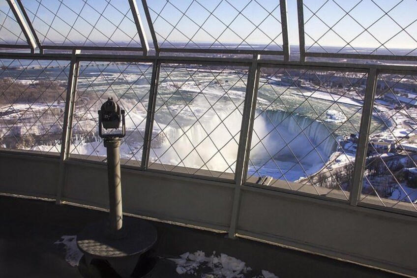 A view of a large ice formation from inside a building with a metal railing. 3