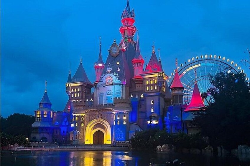 A castle-like building with multiple towers and a large Ferris wheel in the background. 1