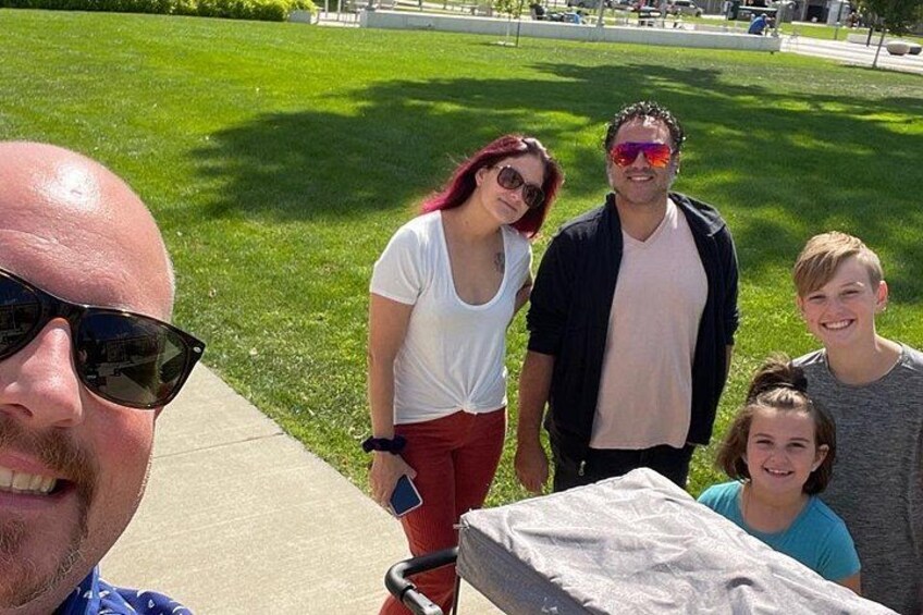 A group of people standing on a grassy area with a stone bench in the foreground. 2