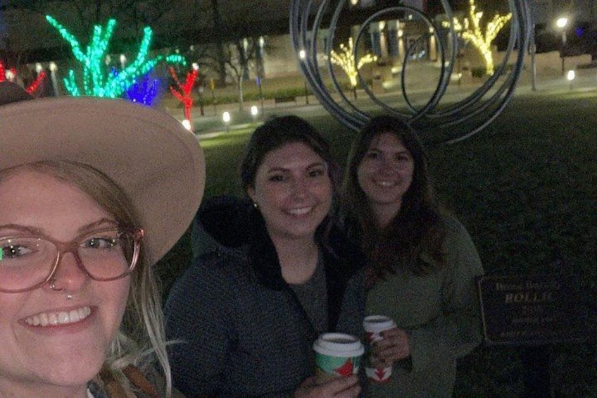 Three people standing in front of a decorative metal sculpture with lights. 2