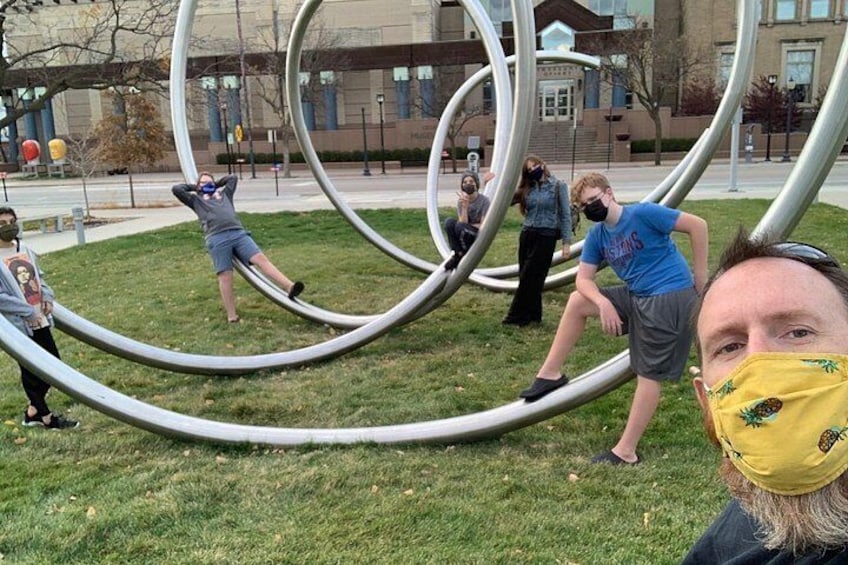 A sculpture of interlocking rings in a park with people interacting with it. 2