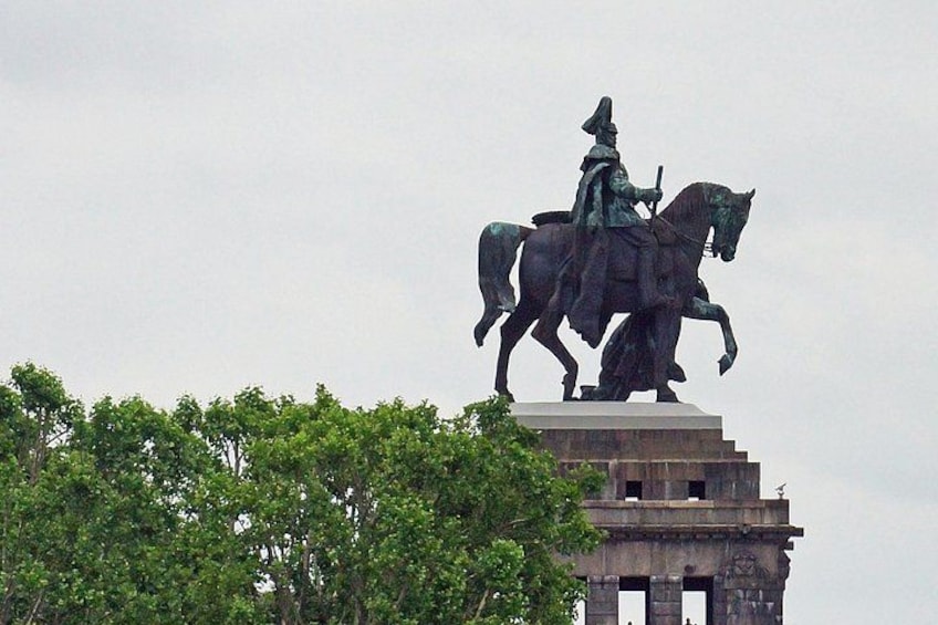 A statue of a person on horseback atop a pedestal, surrounded by trees. 3
