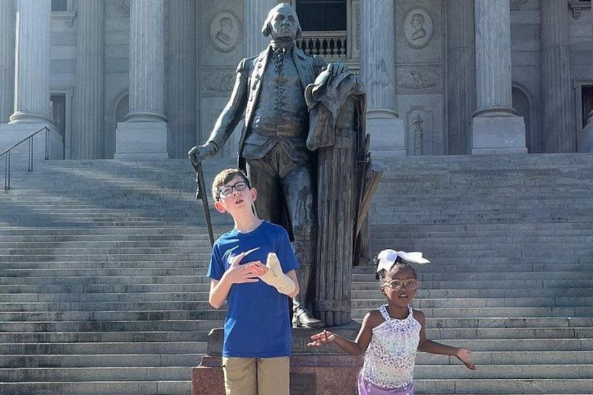 A statue of a historical figure on steps with two people standing in front. 2