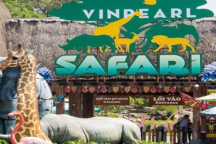 A safari entrance with a giraffe and elephant sculpture, a sign reading 'VINDPEARL SAFARI,' and a welcome sign. 1