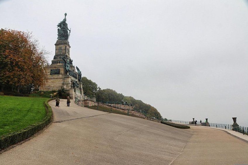A statue on a pedestal, a curved pathway, and a grassy area. 2