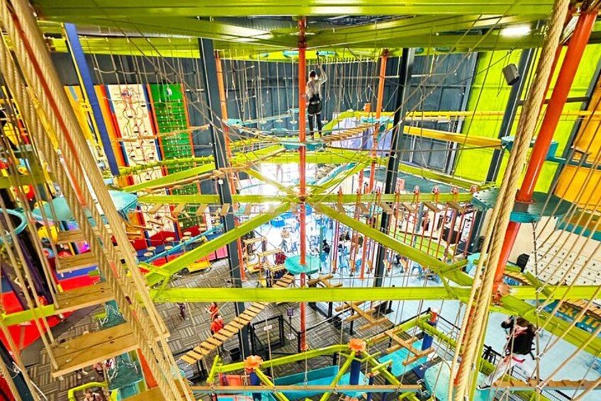 Una estructura de escalada interior de varios niveles con cuerdas y plataformas. 1