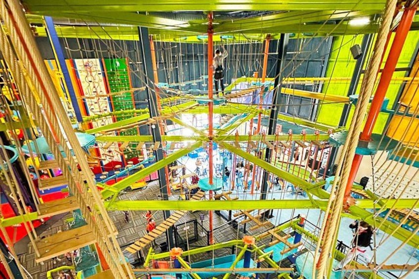 A multi-level indoor climbing structure with various ropes and platforms. 1