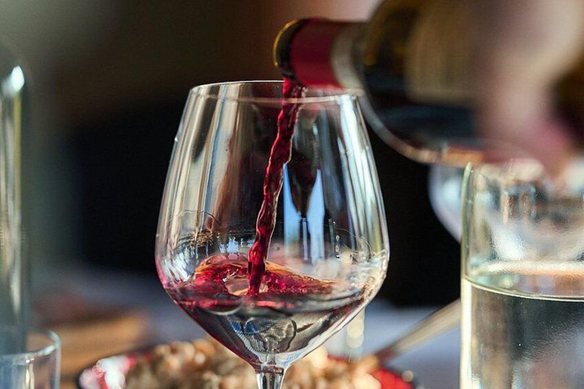Ein Weinglas wird mit Rotwein gefüllt. 1