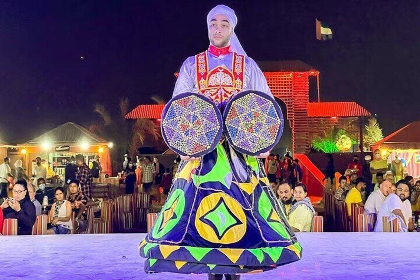 A person in traditional attire performing in front of a crowd at night. 3