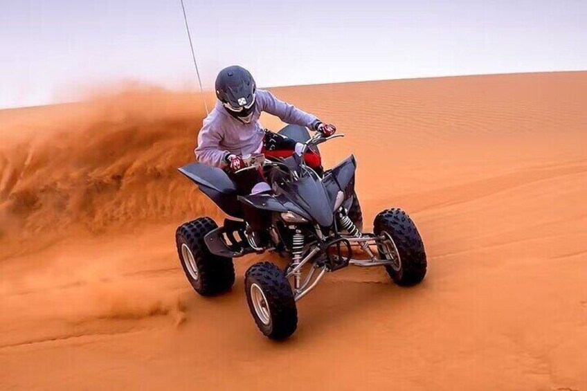 A person riding a quad bike on a sandy dune. 2