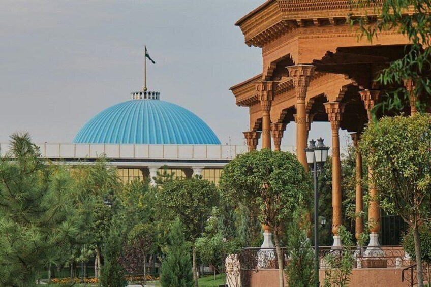 A blue-domed building with a flag, surrounded by greenery and a traditional pavilion. 3