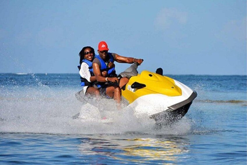 Two people jet-skiing on a body of water. 1