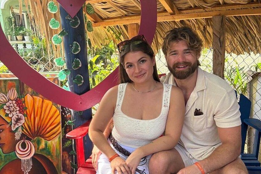 A couple sitting on a bench with a colorful mural in the background. 3