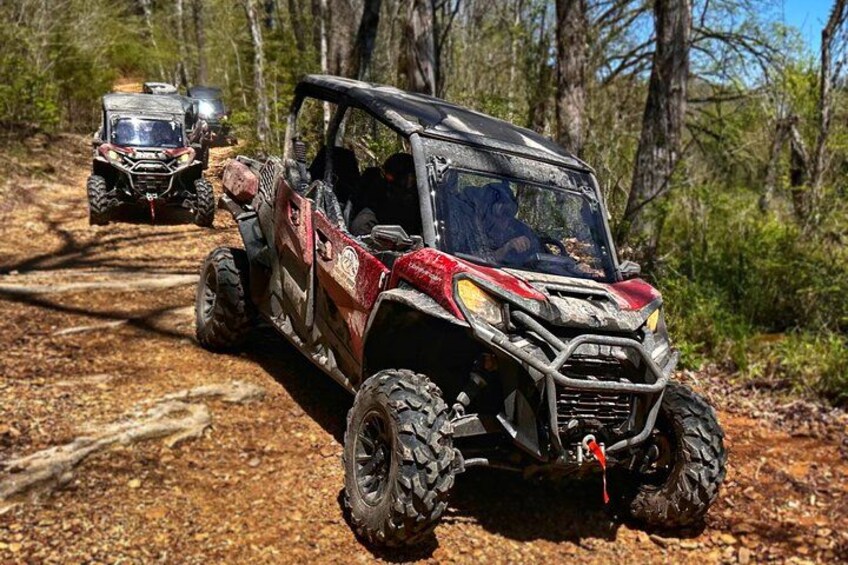 A red off-road vehicle on a dirt path in a wooded area. 2
