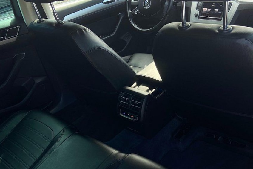 A car interior with leather seats, a steering wheel, and a central console with controls. 2