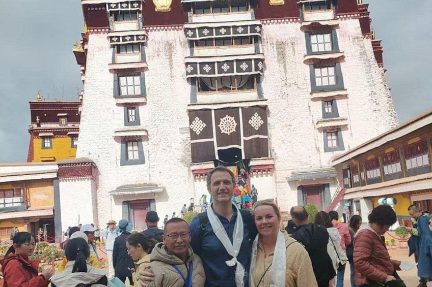 A group of people in front of a traditional building with intricate patterns and multiple windows. 5