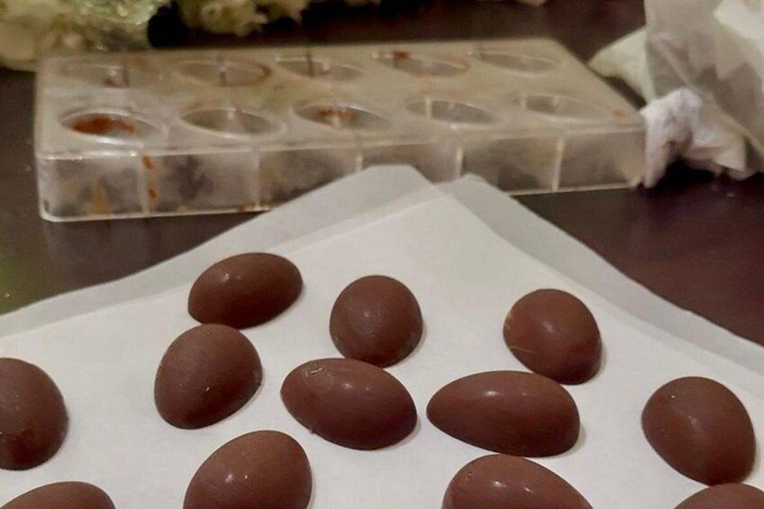 Chocolate eggs on parchment paper with a silicone mold in the background. 4