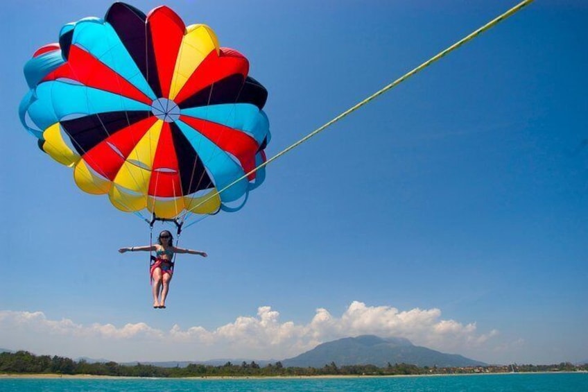 A person skydiving with a colorful parachute over a coastal landscape. 1
