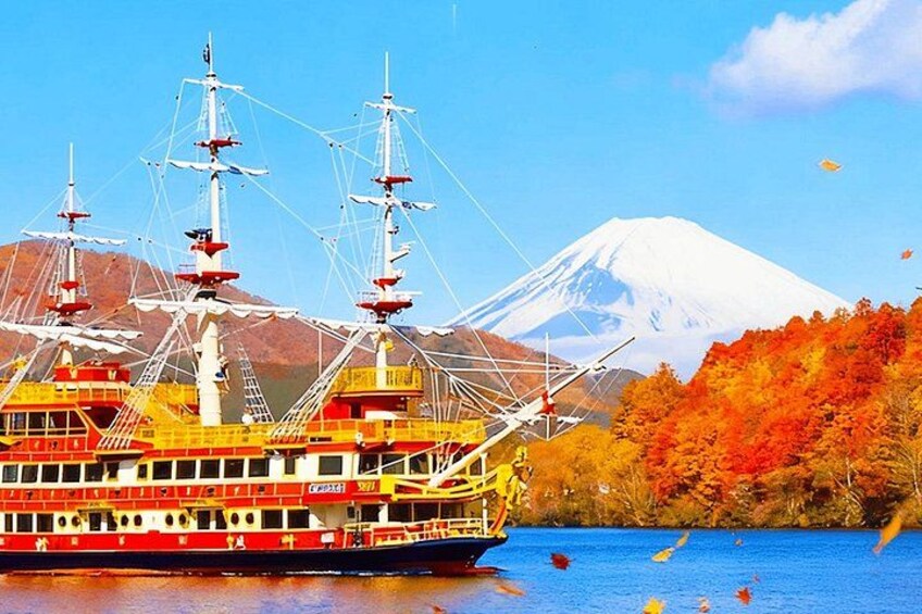 A large red and white cruise ship with multiple decks, a mountainous backdrop, and autumn foliage. 5
