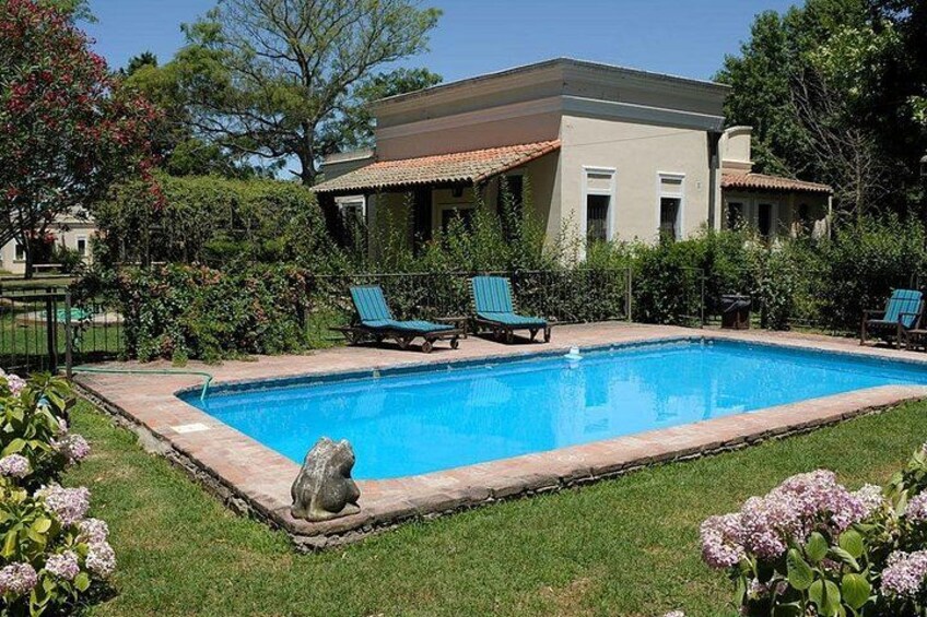 A swimming pool with lounge chairs, a house, and surrounding greenery. 2