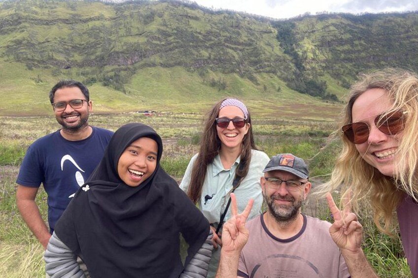 A group of people in a grassy field with hills in the background. 2