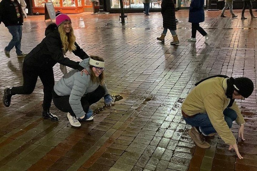 People in a wet urban setting, possibly a plaza, with wet ground and a brick floor. 3