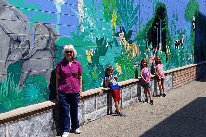 A mural with elephants and giraffes on a wall. 4
