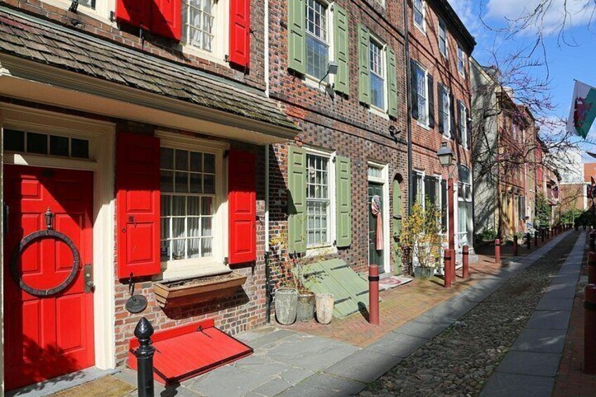 A street with red and green shutters, cobblestone pavement, and a flag. 3