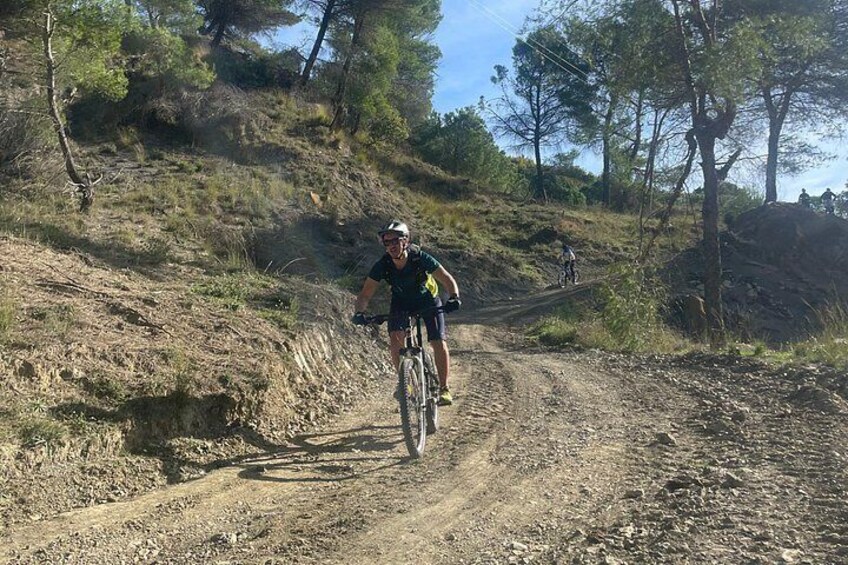 A person riding a mountain bike on a dirt trail surrounded by trees. 3