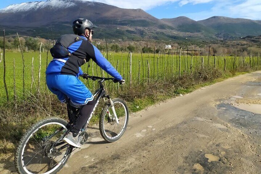 A person riding a mountain bike on a dirt path with a mountainous landscape in the background. 4