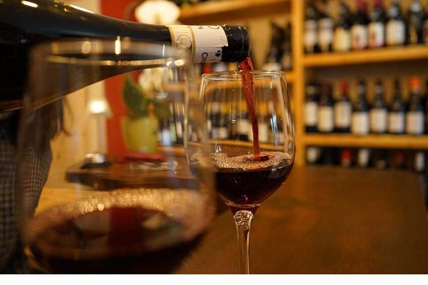 A bottle of red wine being poured into a glass. 4