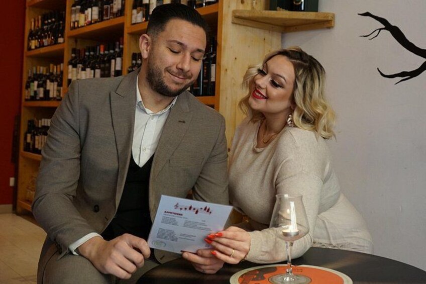 Two people seated at a table with a wine glass and a menu. 3