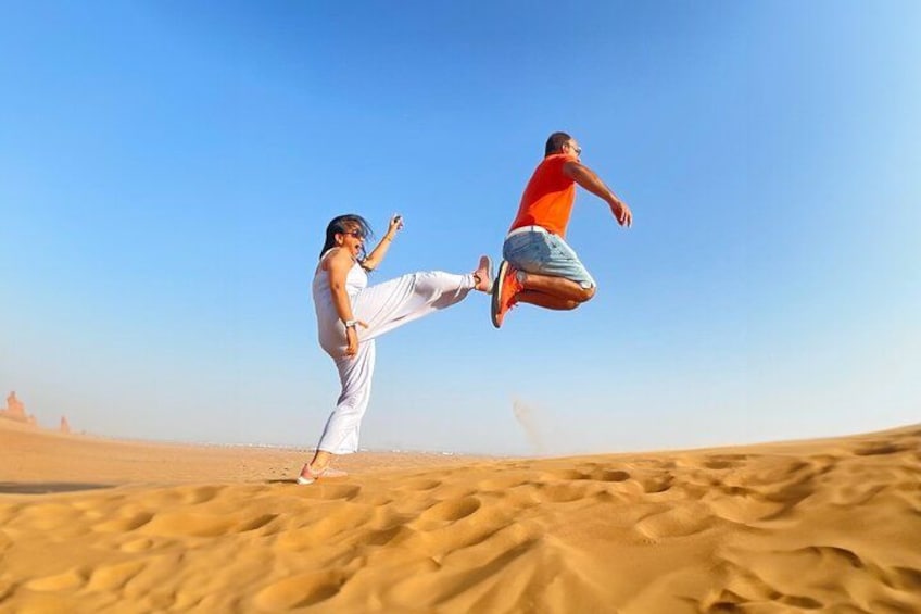 A person performing a high kick in a desert landscape. 2