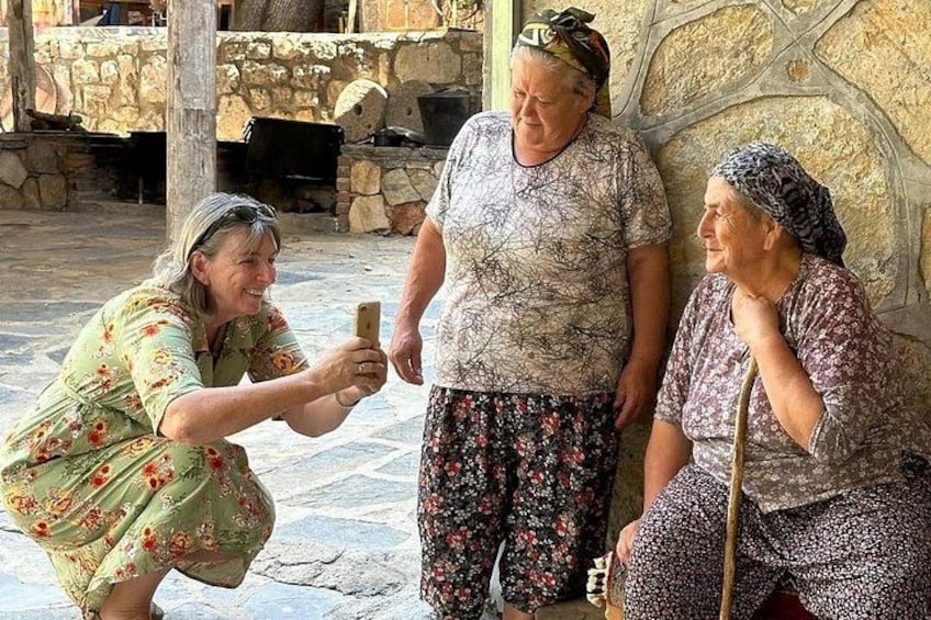 Three people in a stone courtyard with a stone wall and a wooden beam. 1