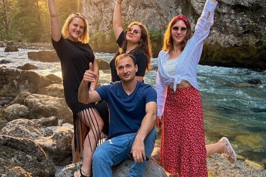 A group of people sitting on rocks by a flowing river. 2