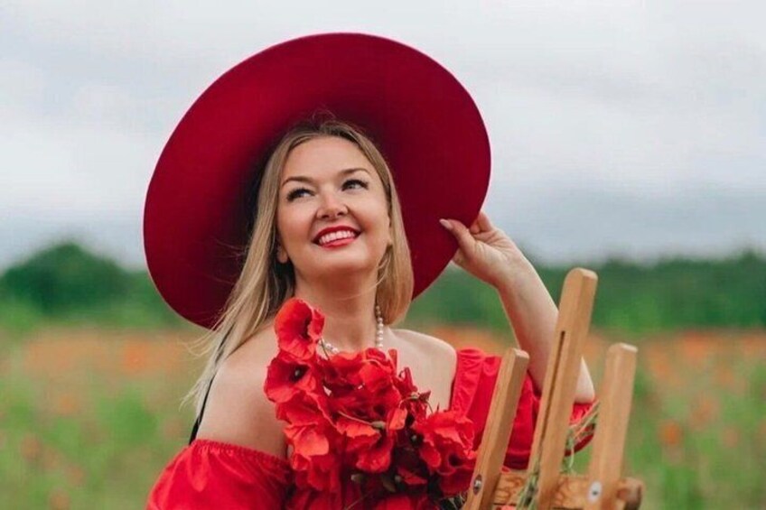 A person holding a red hat and a bouquet of red flowers in a field. 1