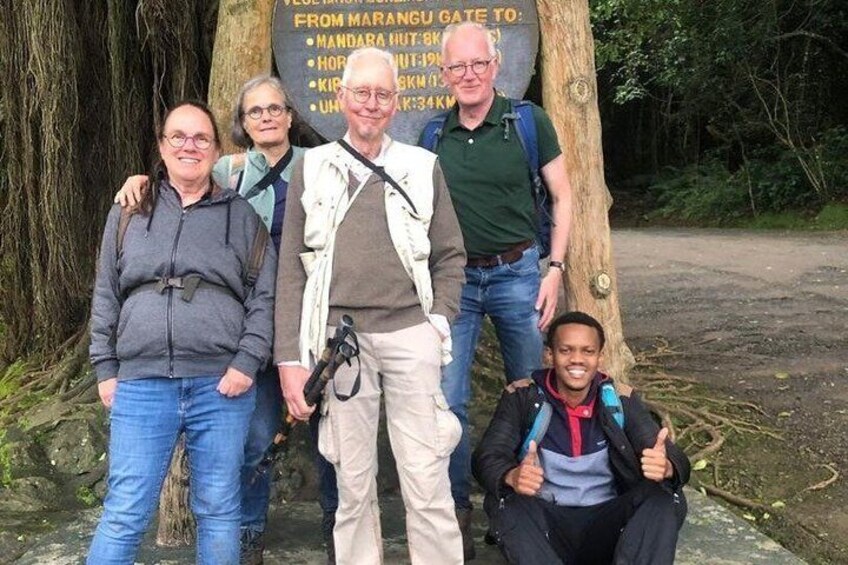 Un groupe de personnes se tient devant un panneau indicateur affichant une liste de destinations. 5