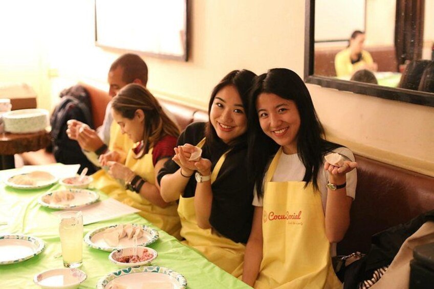 A group of people sitting at a table with food and drinks, wearing aprons. 5