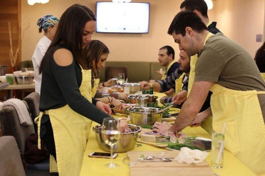 People wearing aprons preparing food at a table. 4