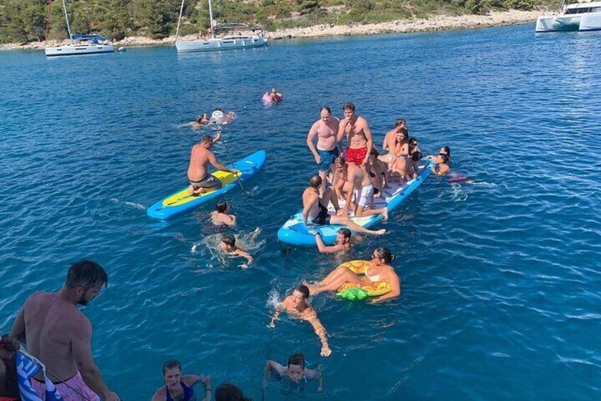 People on a boat, swimming, and a coastline with boats in the background. 3