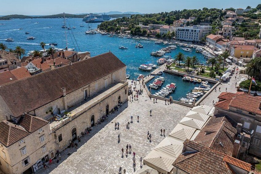 A harbor with boats, a large building, and a town with buildings and trees. 3
