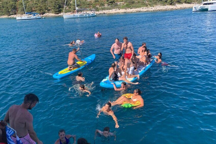 People on a boat, swimming, and a beach with boats in the background. 3