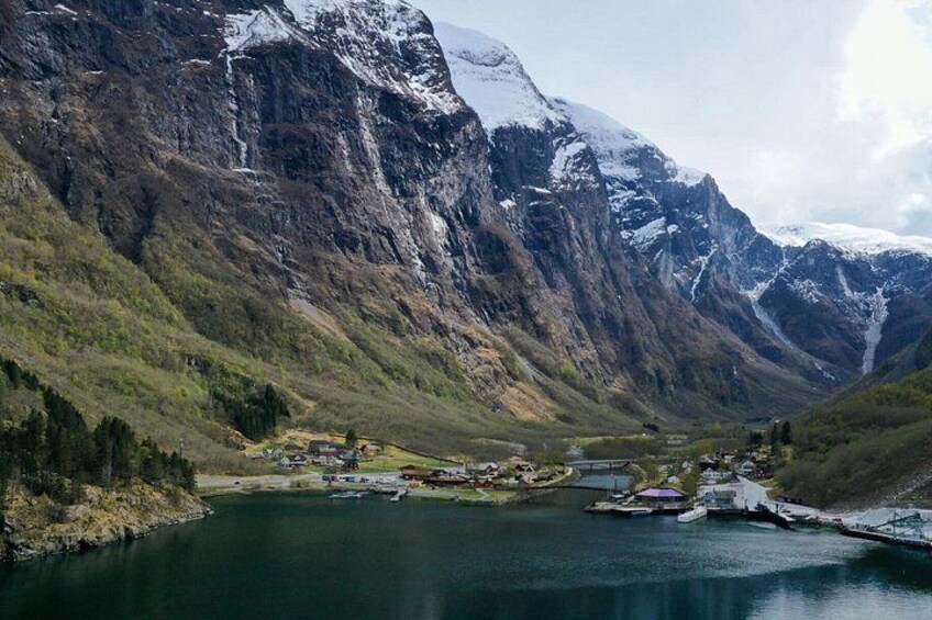 Een bergachtig landschap met een meer, een klein dorp en besneeuwde bergtoppen. 5