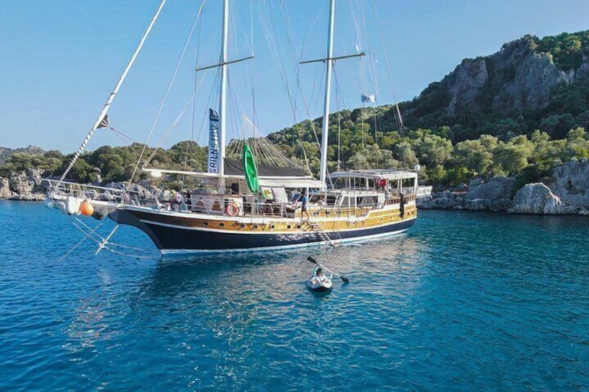 A sailboat docked at a harbor with rocky cliffs in the background. 2