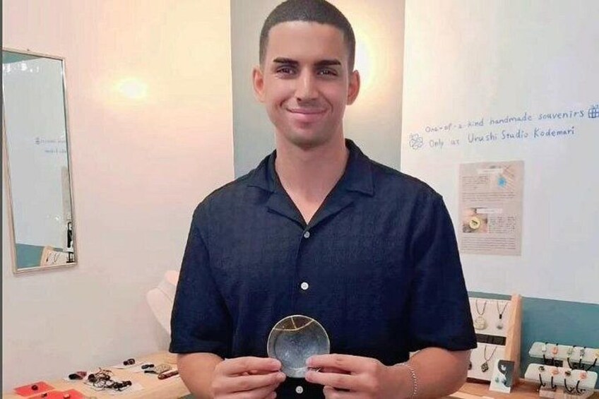 A person holding a circular object, standing in a room with a whiteboard and jewelry display. 2