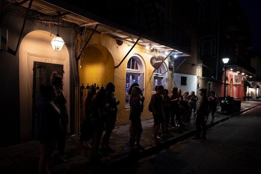 A nighttime street scene with people standing outside a building with a sign that reads 'Germano.' 2