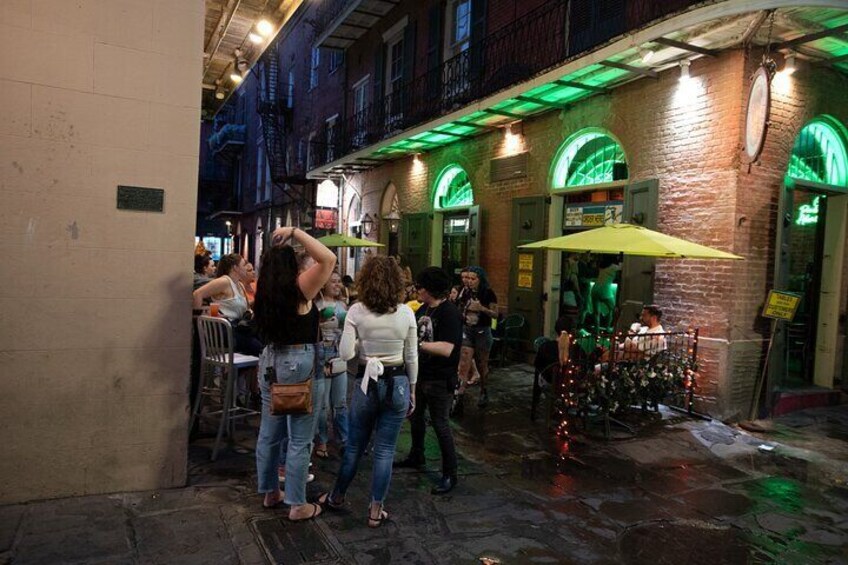 Una calle iluminada de noche con gente parada y caminando. 4